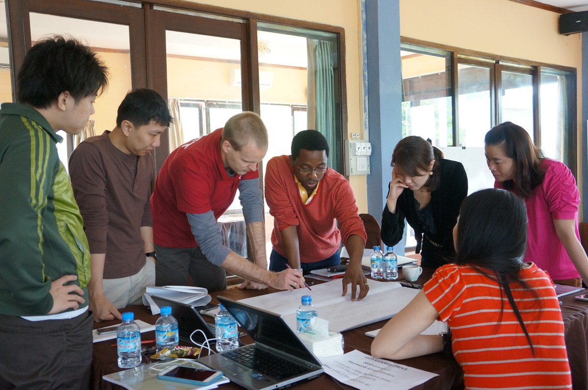 A diverse GIFT participant team works together around a table on its project proposal
